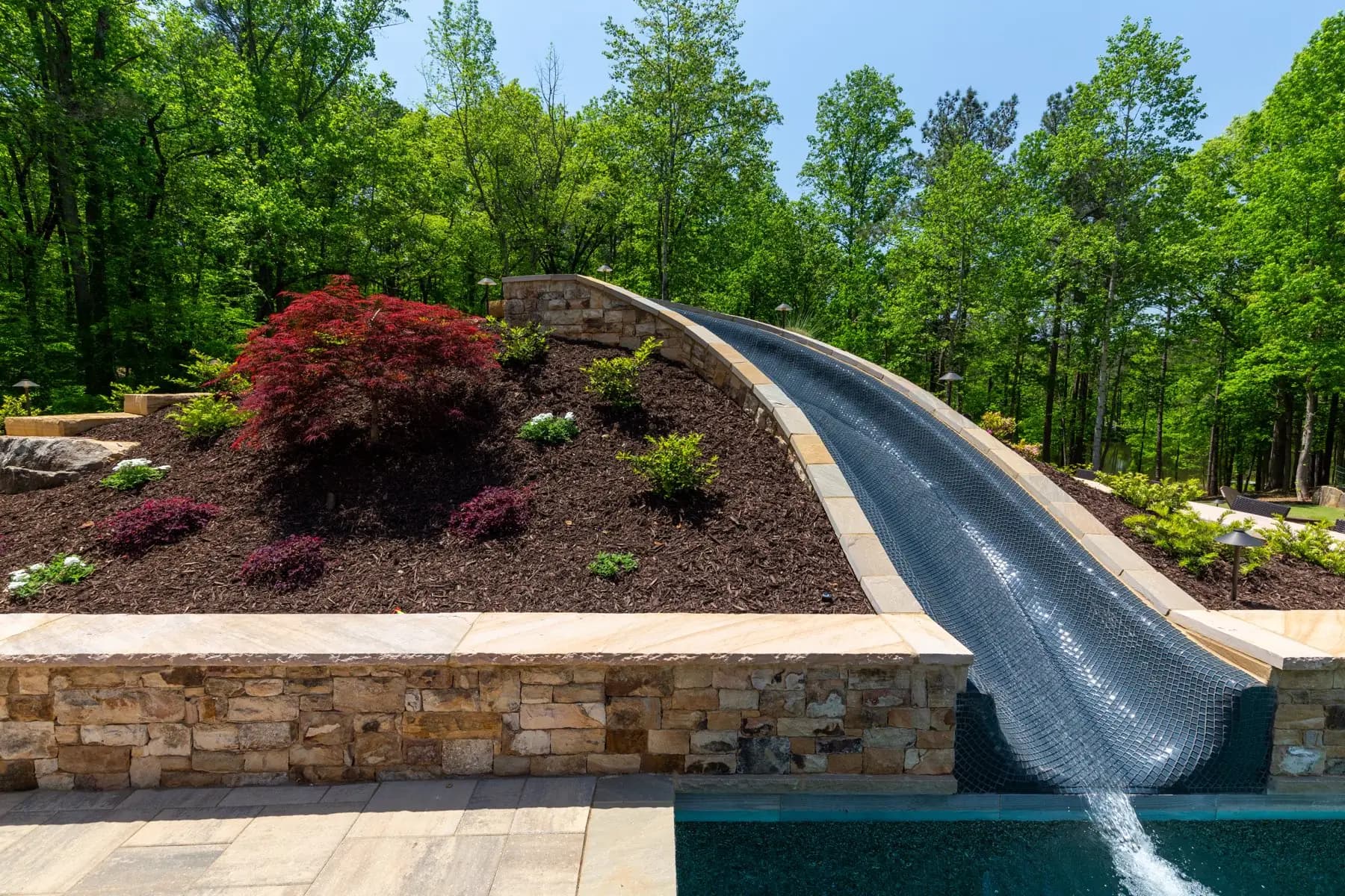 The Batchelor water slide set into planted stone beside the pool in Roswell
