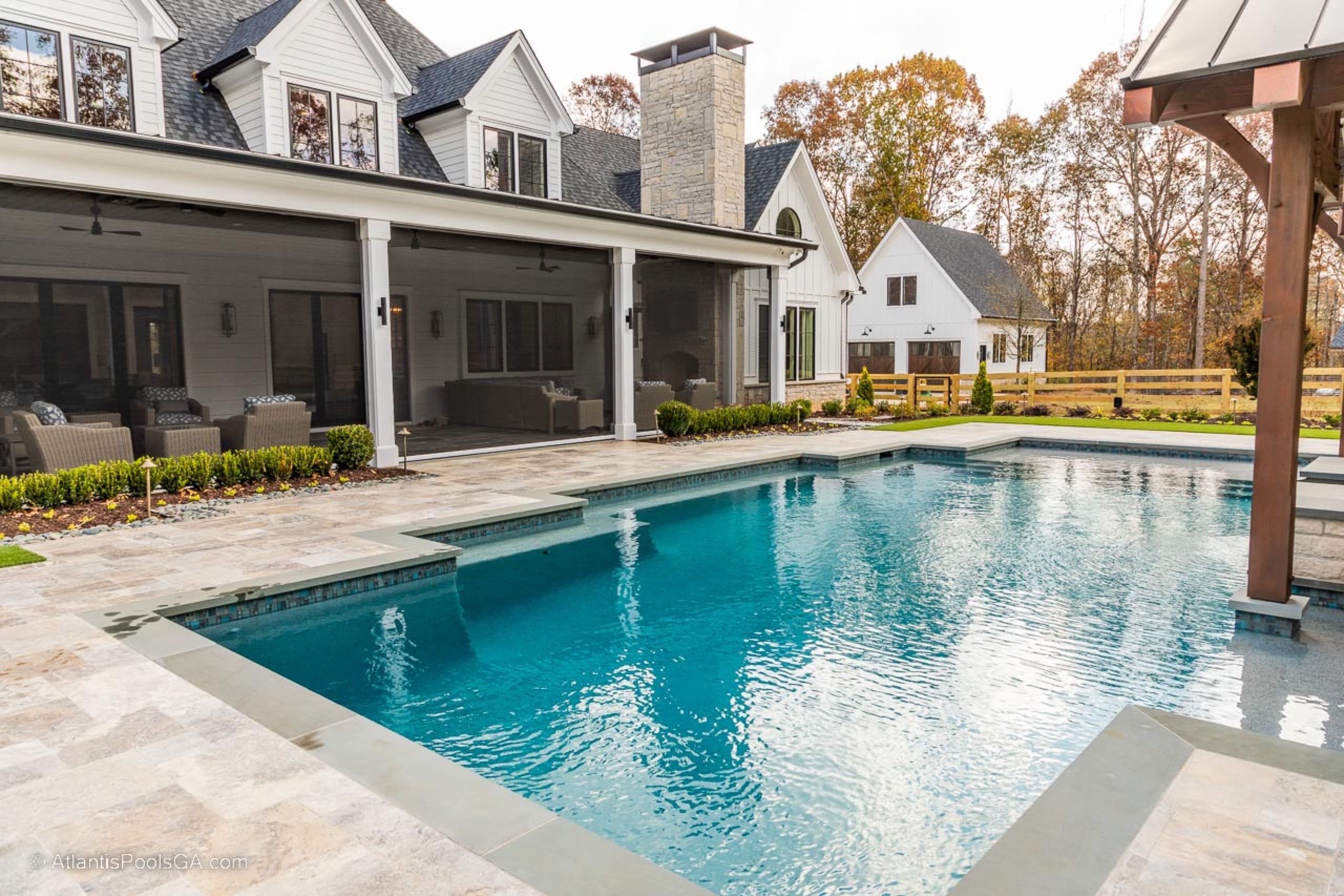 The Bolduc pool aligned with a white farmhouse and deep covered porch
