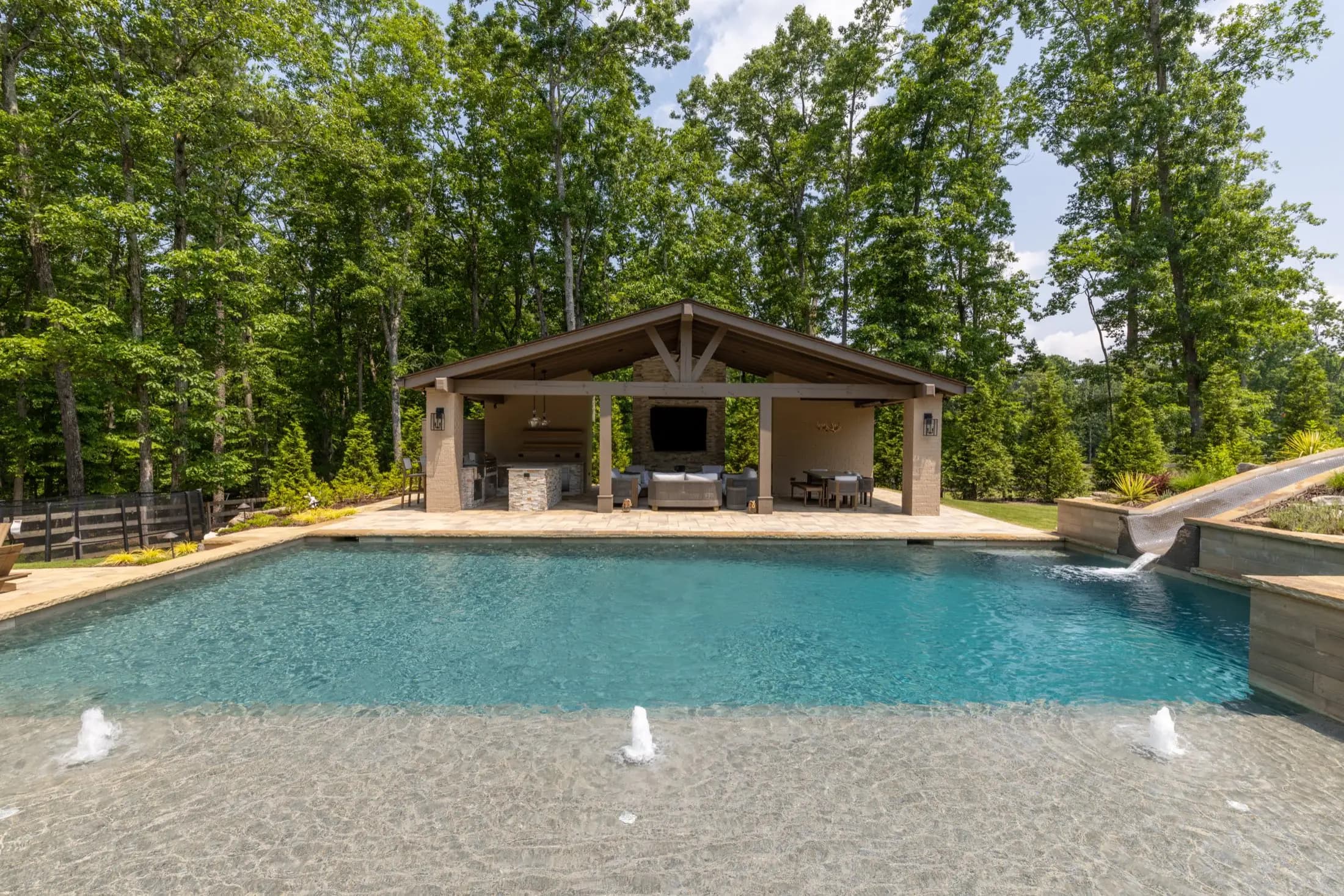 The covered pavilion and outdoor kitchen behind fountain jets at the Kahtri pool in Roswell
