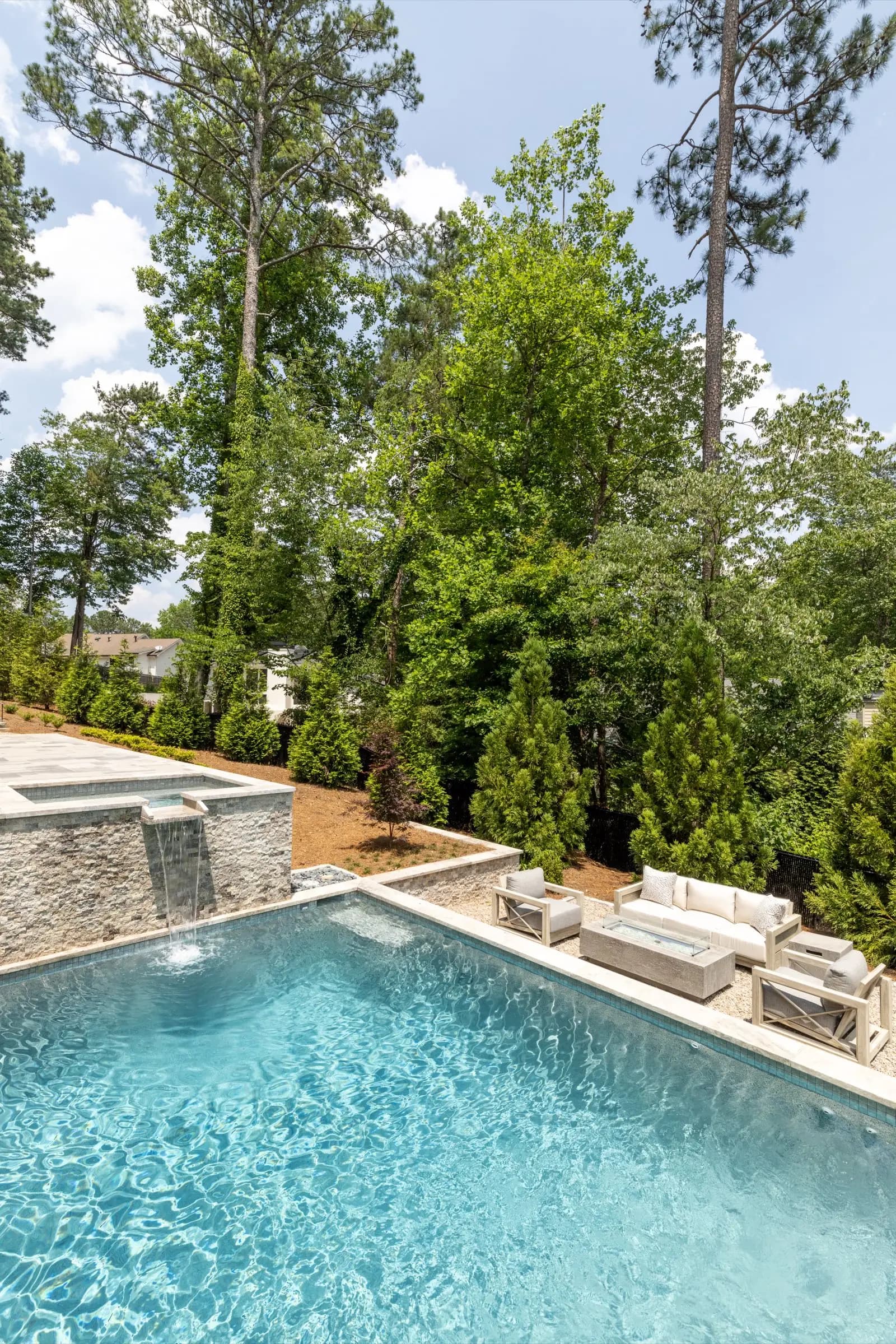 A raised spa spilling toward the pool below it, the two water features reading as one design.