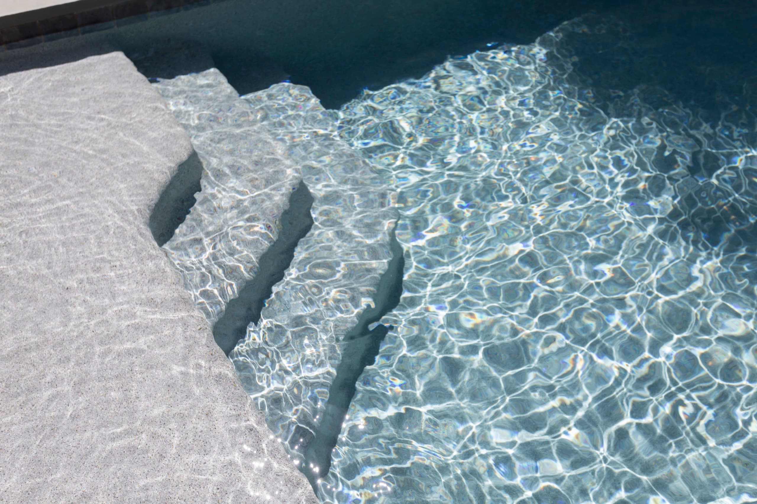 Hand-set stone steps descending into clear pebble-finish water at the Nichol project in Canton