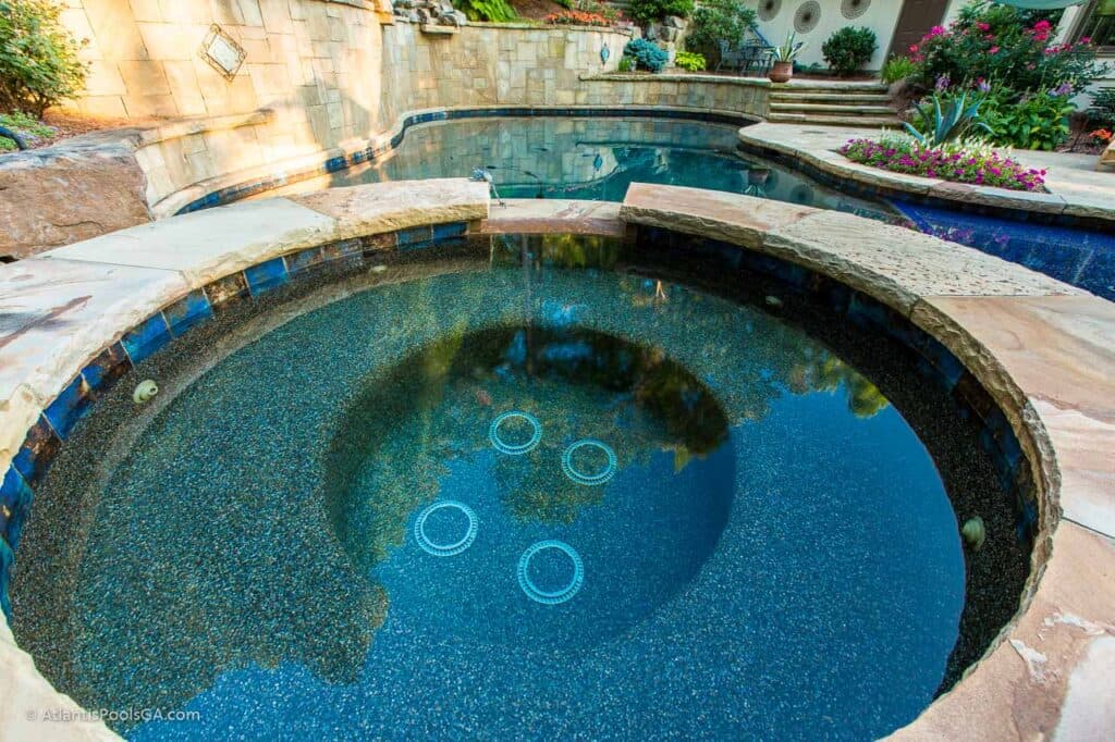 A circular in-pool spa with blue mosaic tile and hydrotherapy jets
