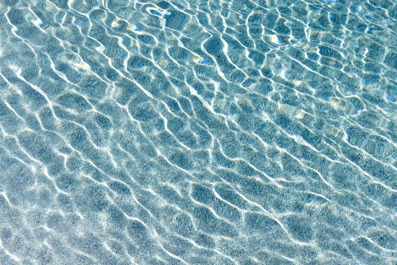Close-up drift of pool water, sunlight moving across the surface