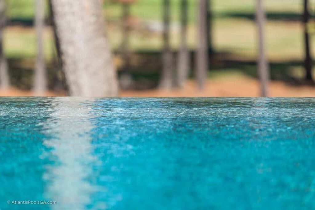 A vanishing-edge pool holding a flat waterline against the treeline, an example of Atlantis's vanishing edge pool type