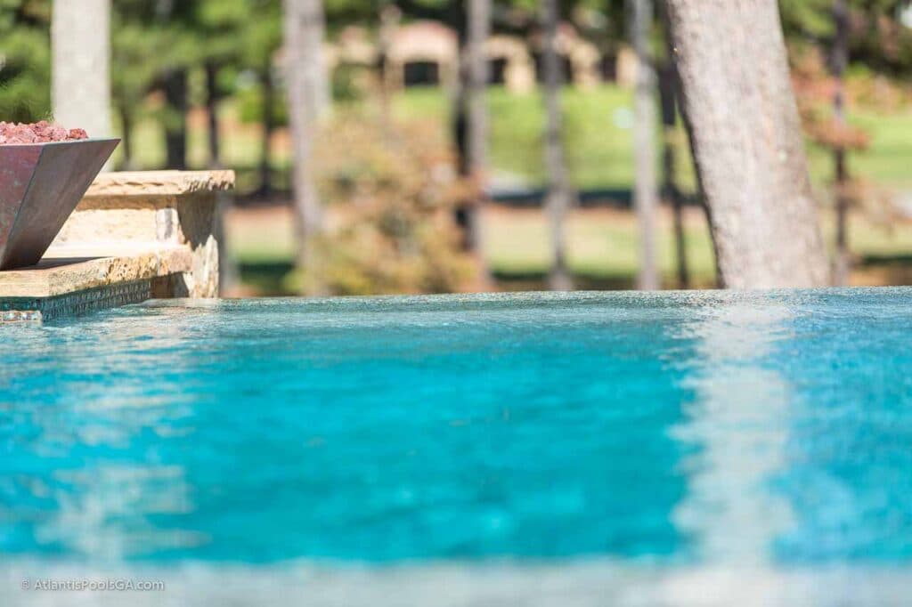 A vanishing edge pool spillway detail, glass tile visible along the drop